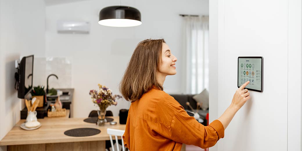 Frau bedient das Touch-Display ihres Smart Home Panels an der Wand